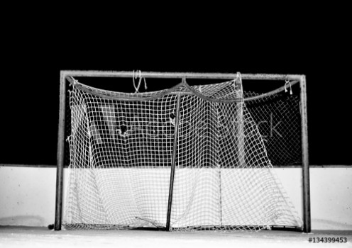Picture of Close-up of tattered and frayed mesh on a hockey net on an outdoor ice skating rink at night in black and white